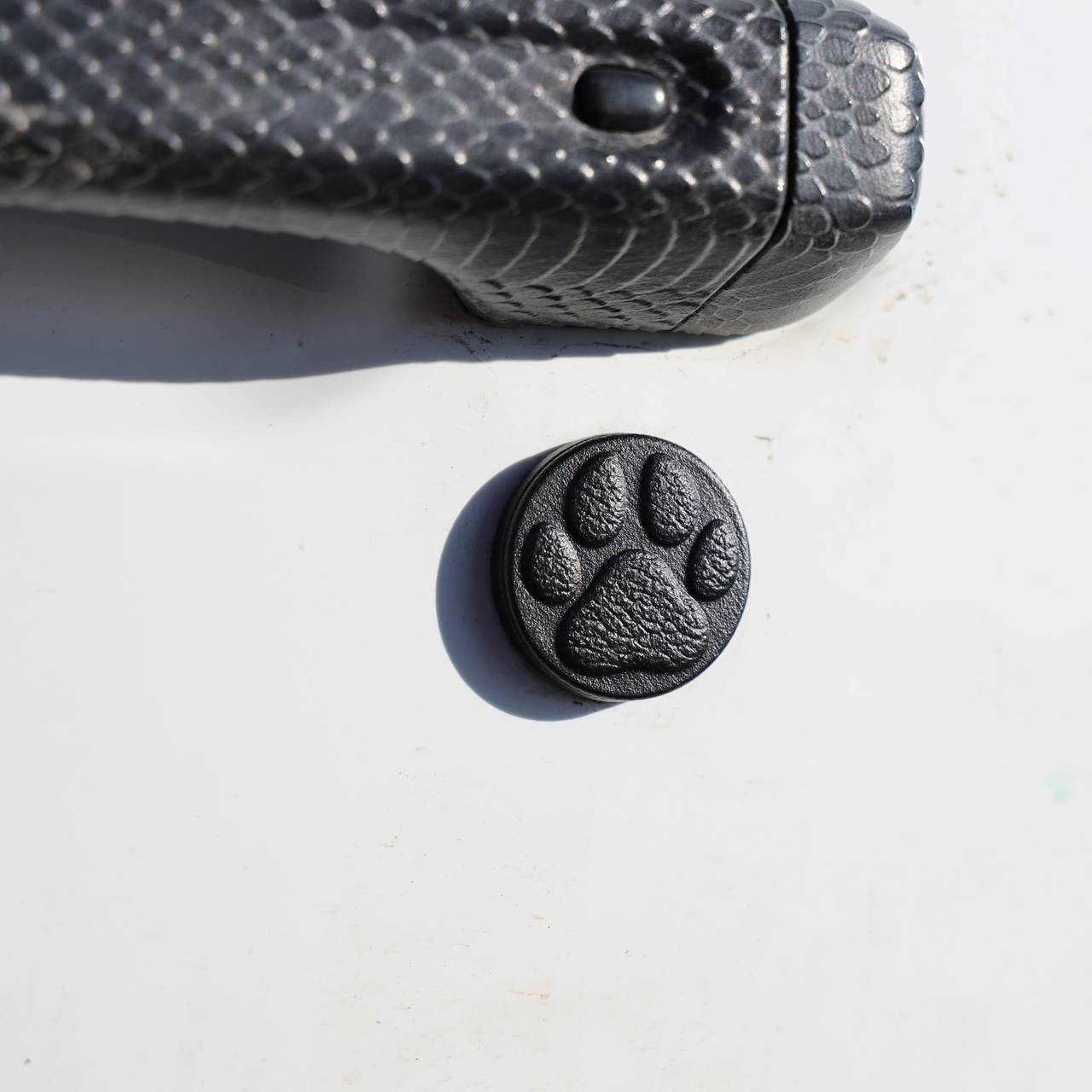A black key lock cap with a embossed paw print design on a white surface.